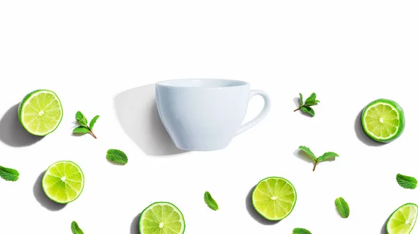Fresh limes with tea cup overhead view — Stock Photo, Image