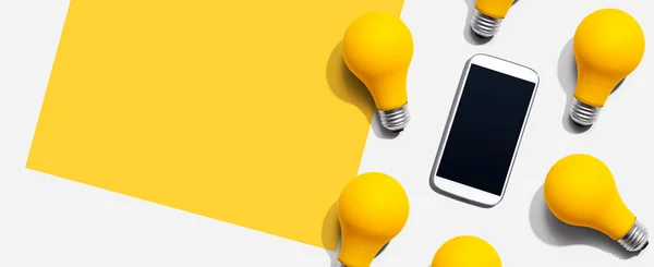 黄色の電球付きのスマートフォン — ストック写真