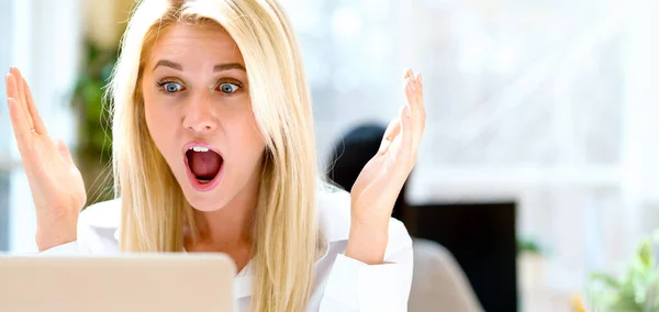 Verrast jonge vrouw zit aan haar bureau — Stockfoto