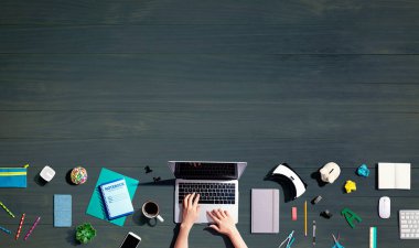 Ofis malzemesi olan bir dizüstü bilgisayar kullanan kişi.