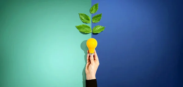 Persona sosteniendo una bombilla con hojas verdes — Foto de Stock