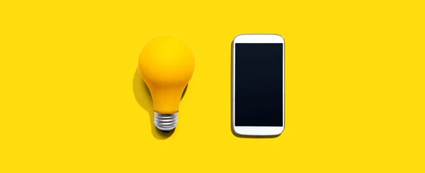 Smartphone met gele gloeilamp — Stockfoto