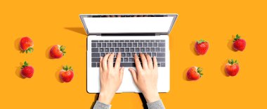 Taze çilekli dizüstü bilgisayar kullanan bir kadın.