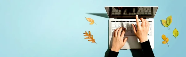 Autumn leaves with person using a laptop computer — Stock Photo, Image