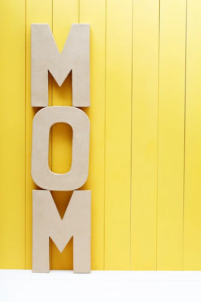 MOM letras de texto sobre fundo de madeira amarelo — Fotografia de Stock