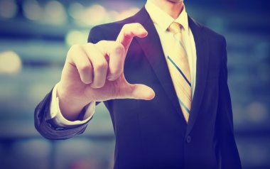 Parmaklarının arasında bir şey tutan iş adamı