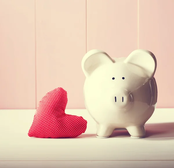 Piggy bank with red heart pillow — Stock Photo, Image