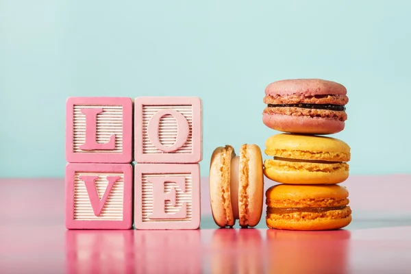 Macarons mit Liebesbotschaft auf Holzklötzen — Stockfoto