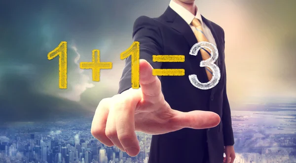 Businessman pointing at synergy concept above the city — Stock Photo, Image