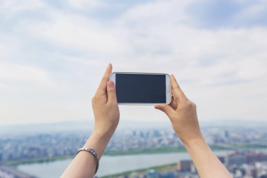 Bir smartphone bir şehir arka planda tutan kişi