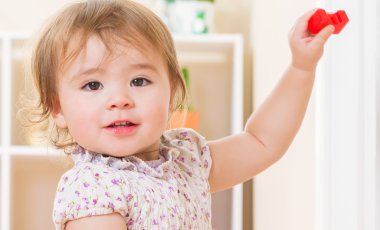 Gülümseyen yürümeye başlayan çocuk oyuncak bloklarla oynama