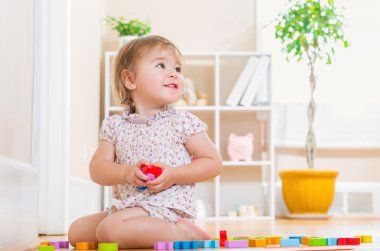 Gülümseyen ve oyuncak bloklarla oynama yürümeye başlayan çocuk kız