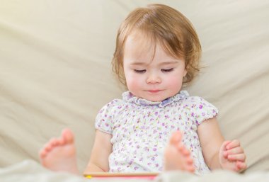 Bir tablet bilgisayar kullanan mutlu yürümeye başlayan çocuk kız