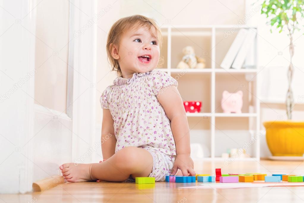 Toddler girl playing with wooden toy blocks