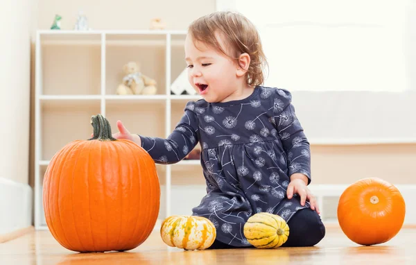 Gelukkig peuter meisje spelen met pompoenen — Stockfoto