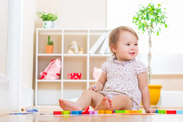 微笑着蹒跚学步的女孩玩她的玩具积木 — 图库照片