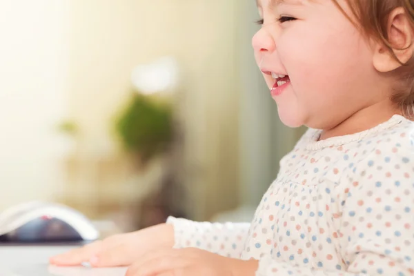 Gelukkig lachend peuter meisje met haar computer — Stockfoto