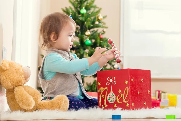 Девушка играет со своими подарками под елкой — стоковое фото