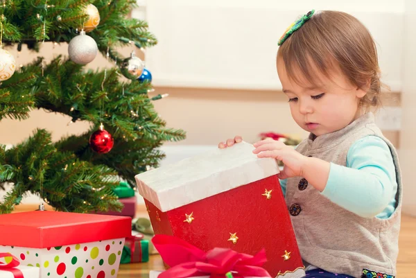 Girl opening presents under her Christmas tree — Stock Photo, Image