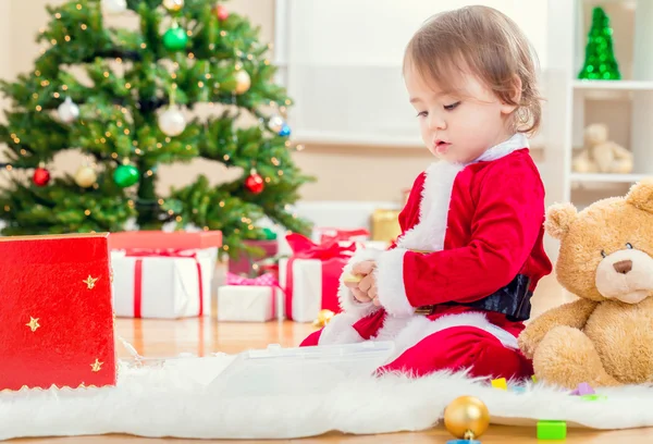 Κορίτσι σε ένα κοστούμι santa παίζοντας το χριστουγεννιάτικο δέντρο — Φωτογραφία Αρχείου