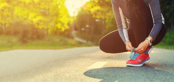 Femeie alergător leagă pantofii ei pregătindu-se pentru o jogging — Fotografie, imagine de stoc