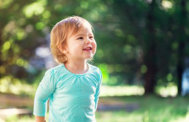 Dışarıda gülümseyen mutlu yürümeye başlayan çocuk kız