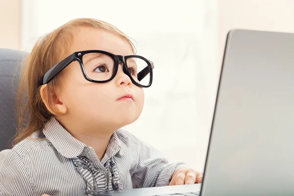 Slimme peuter meisje in grote glazen met behulp van haar laptop — Stockfoto