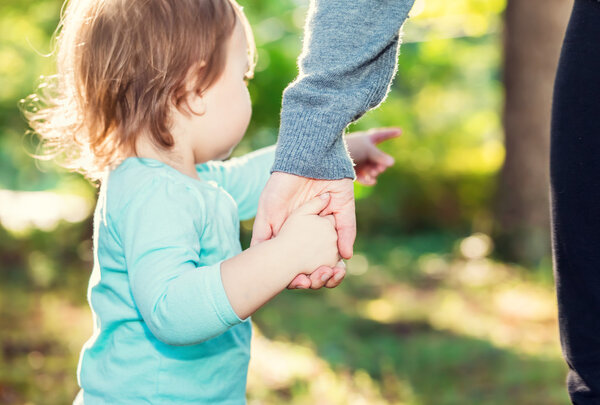 Toddler girl holding hands with her mother