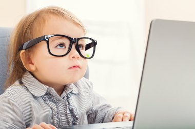 Onu laptop kullanırken büyük gözlüklü akıllı yürümeye başlayan çocuk kız