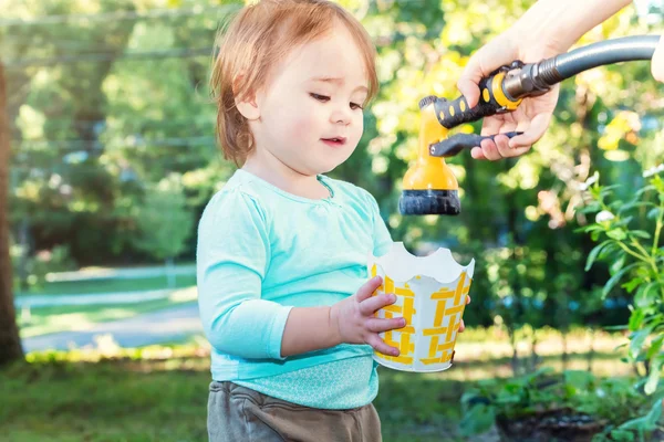 Happy toddler girl playing with water outside — Stock Photo, Image