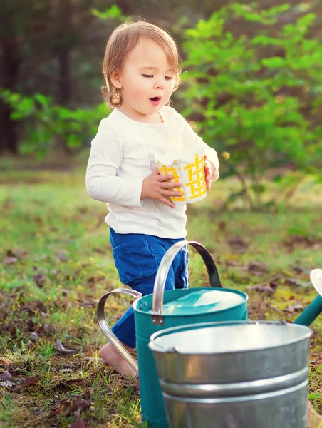 Happy toddler girl playing with watering cans — Stock Photo, Image