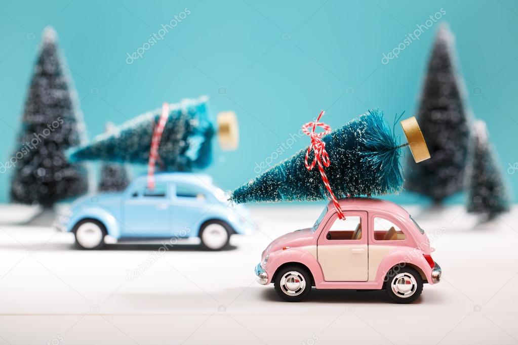 Cars carrying Christmas trees in miniature evergreen forest