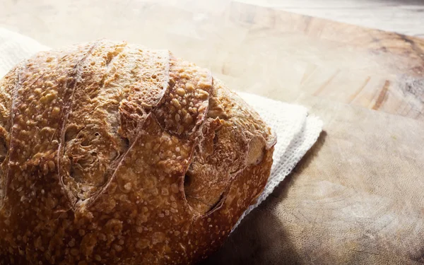 Буханка хлеба на деревенском фоне разделочной доски — стоковое фото