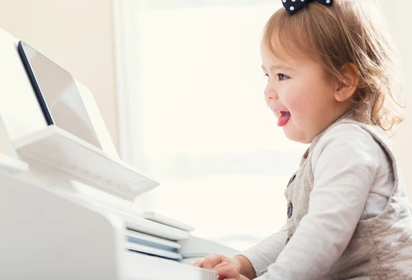 Happy toddler girl laughing and playing the piano — Stock Photo, Image