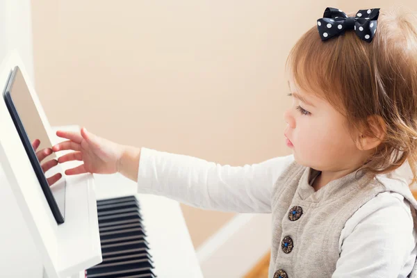 Ragazza bambino che suona il pianoforte con l'aiuto del suo tablet — Foto Stock