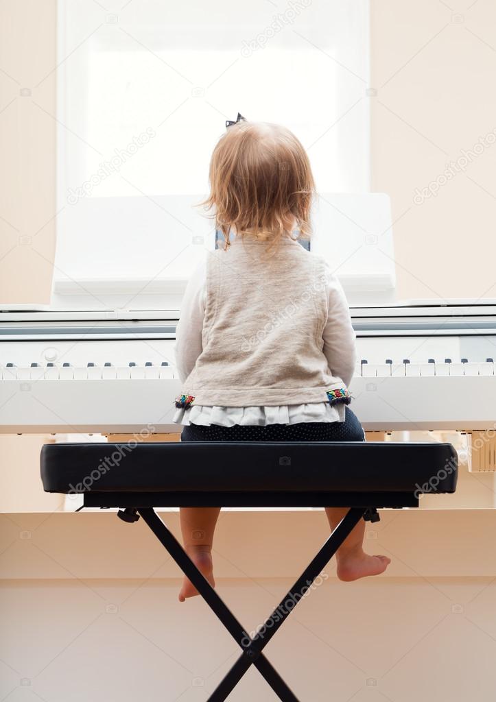Happy toddler girl playing the piano