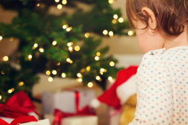 Hediyeler Noel ağacı önünde açarak yürümeye başlayan çocuk kız