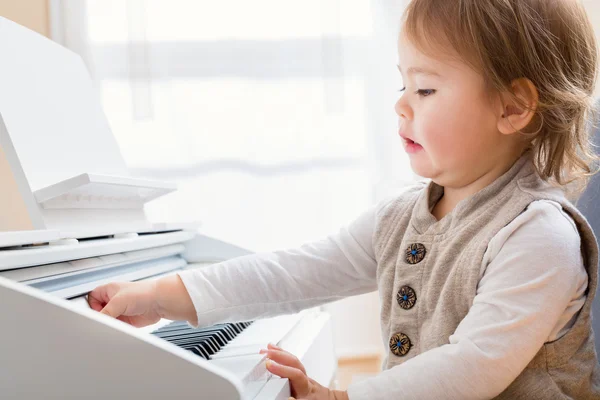 Barn girl att göra ett roligt uttryck när du spelar piano — Stockfoto
