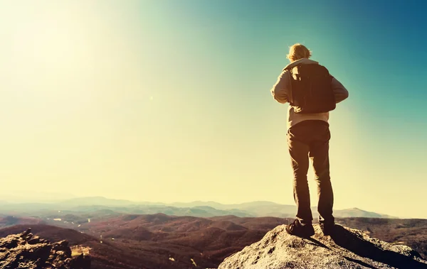 Uomo in piedi sul bordo di una scogliera che domina le montagne — Foto Stock