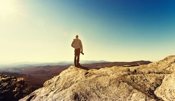 Hombre de pie en un borde de acantilados con vistas a las montañas de abajo —  Fotos de Stock