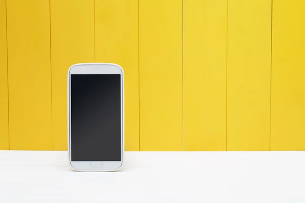 Teléfono inteligente sobre fondo de madera amarillo — Foto de Stock