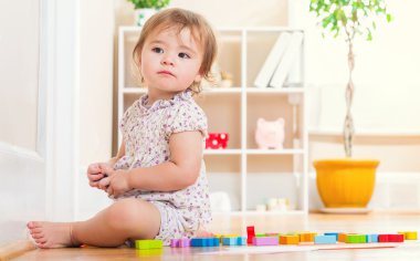 Onun oyuncakları ile oynarken mutlu yürümeye başlayan çocuk kız 