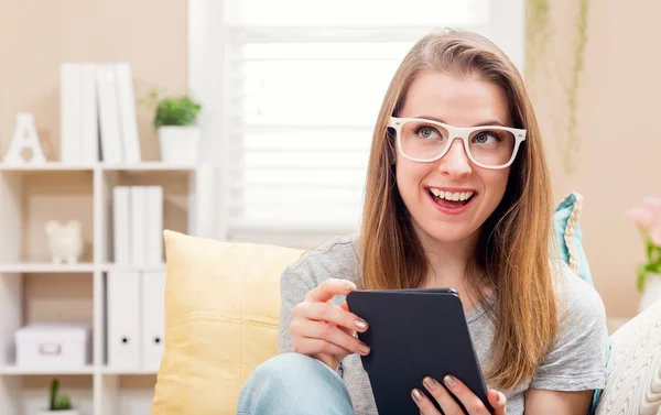 Щаслива молода жінка читає електронну книгу на дивані — стокове фото