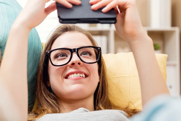 Mutlu genç kadın onun kanepede bir e-kitap okuma — Stok fotoğraf