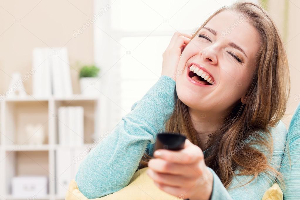 Young woman laughing while watching TV 