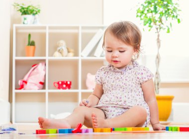 Onun oyuncakları ile oynarken mutlu yürümeye başlayan çocuk kız 