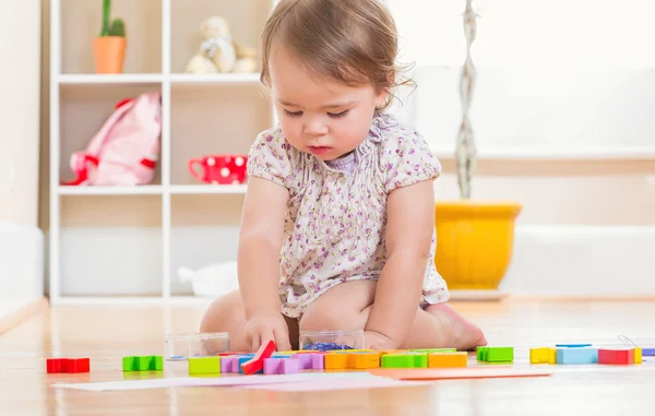 Batole dívka si hraje s hračkami, uvnitř — Stock fotografie