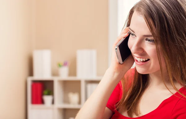 Счастливая молодая женщина говорит по телефону в своем офисе — стоковое фото