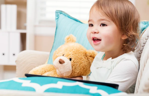 Menina feliz com seu ursinho de pelúcia e tablet pc — Fotografia de Stock