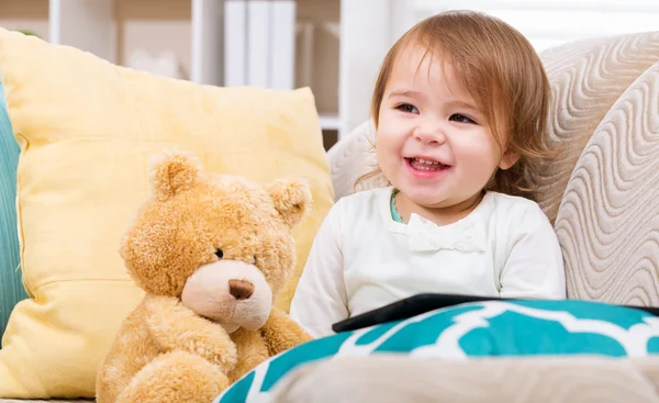 Menina feliz com seu ursinho de pelúcia e tablet pc — Fotografia de Stock